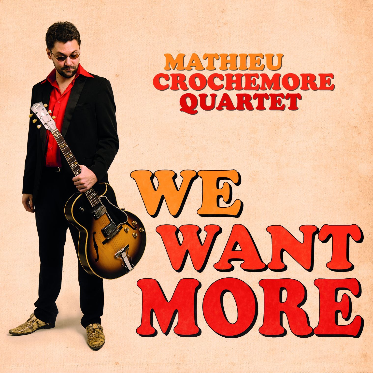 Pochette de l’album « We Want More » : Mathieu Crochemore en costume noir et chemise rouge, sa guitare à la main, sur un fond de carton clair.