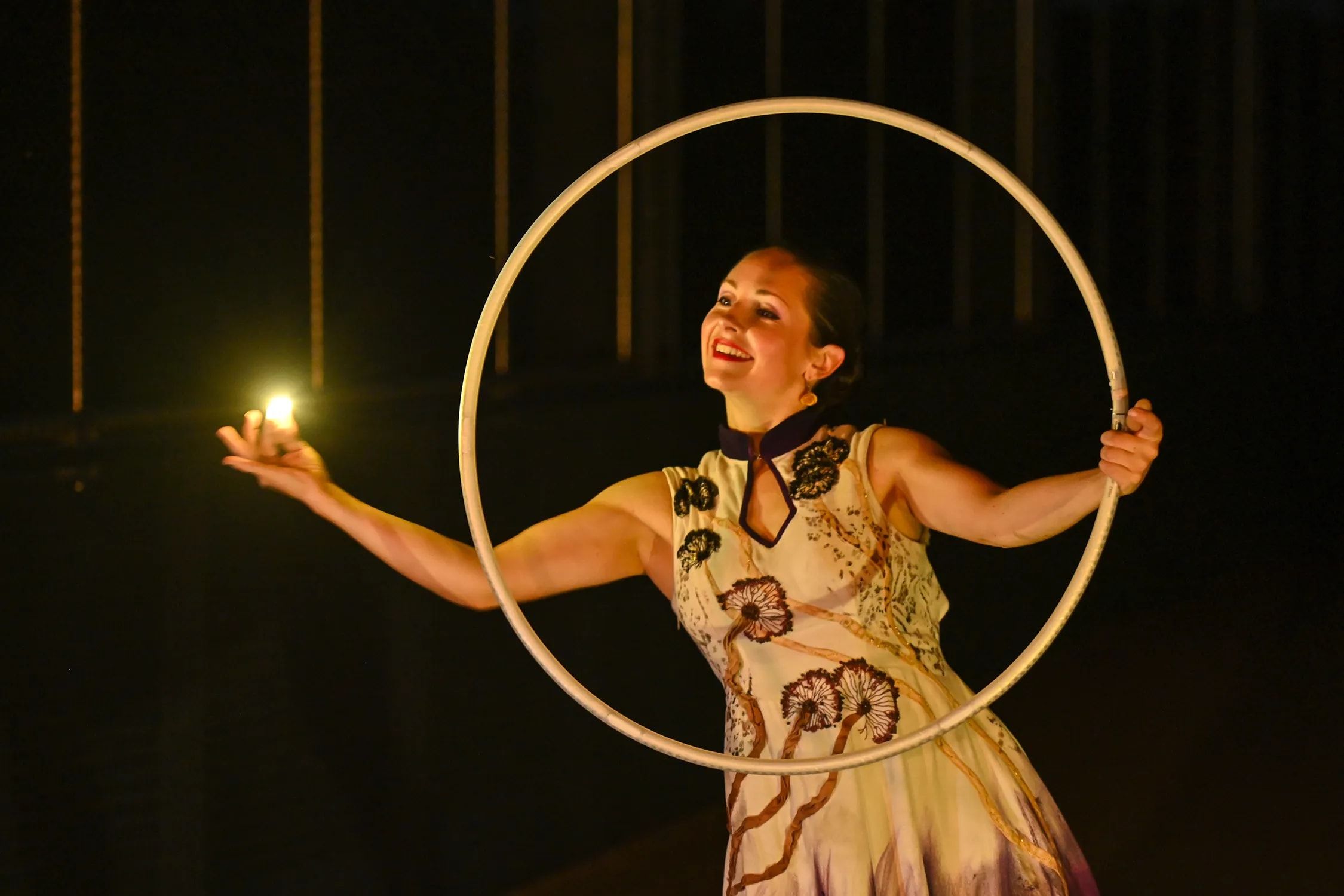 La nuit, la danseuse sourit dans son cerceau, une petite flamme posée dans la main.