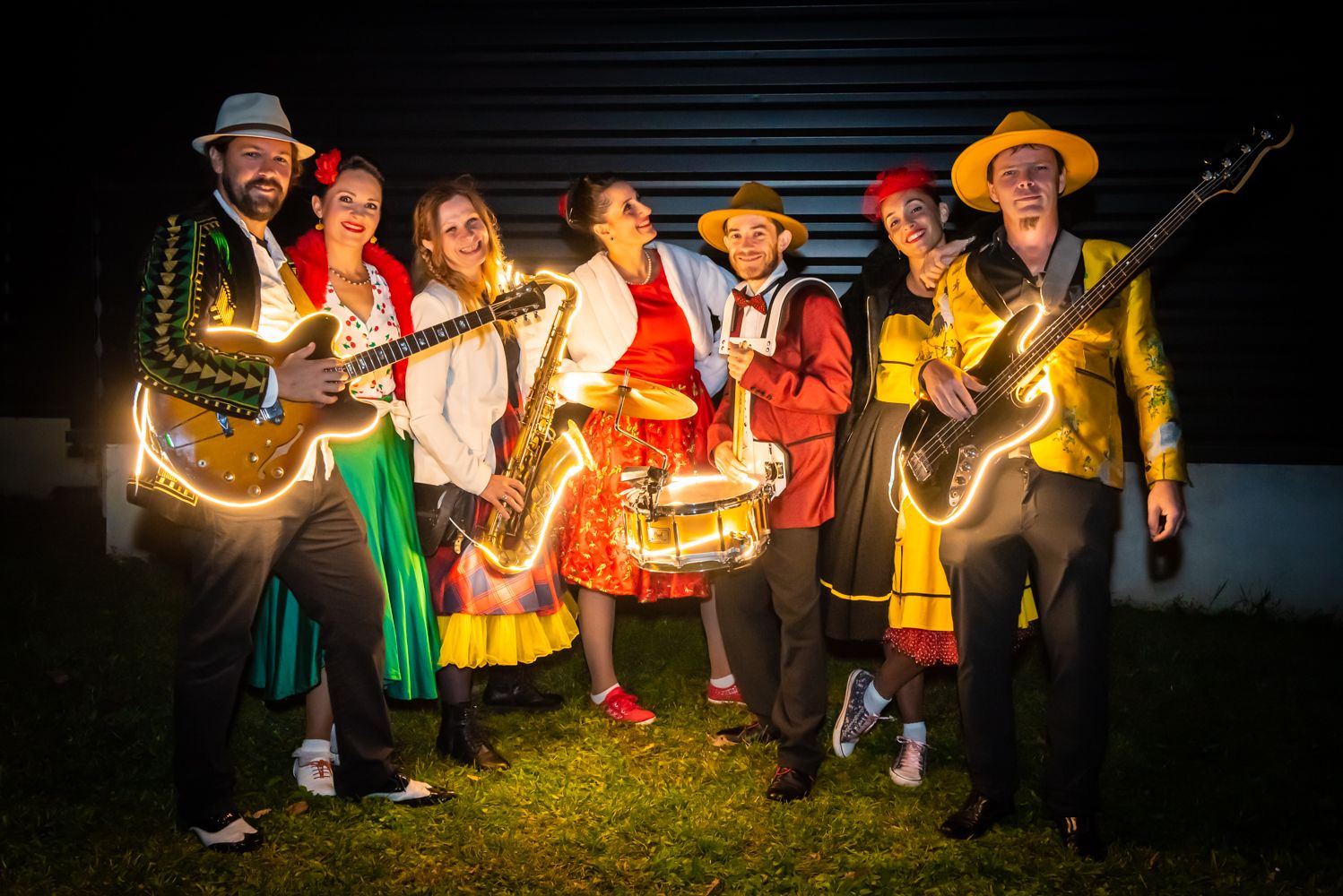 La nuit, les musiciens et les danseuses de Streetside en costumes d’été, guitares, saxophone et caisse claire bordés de leds.