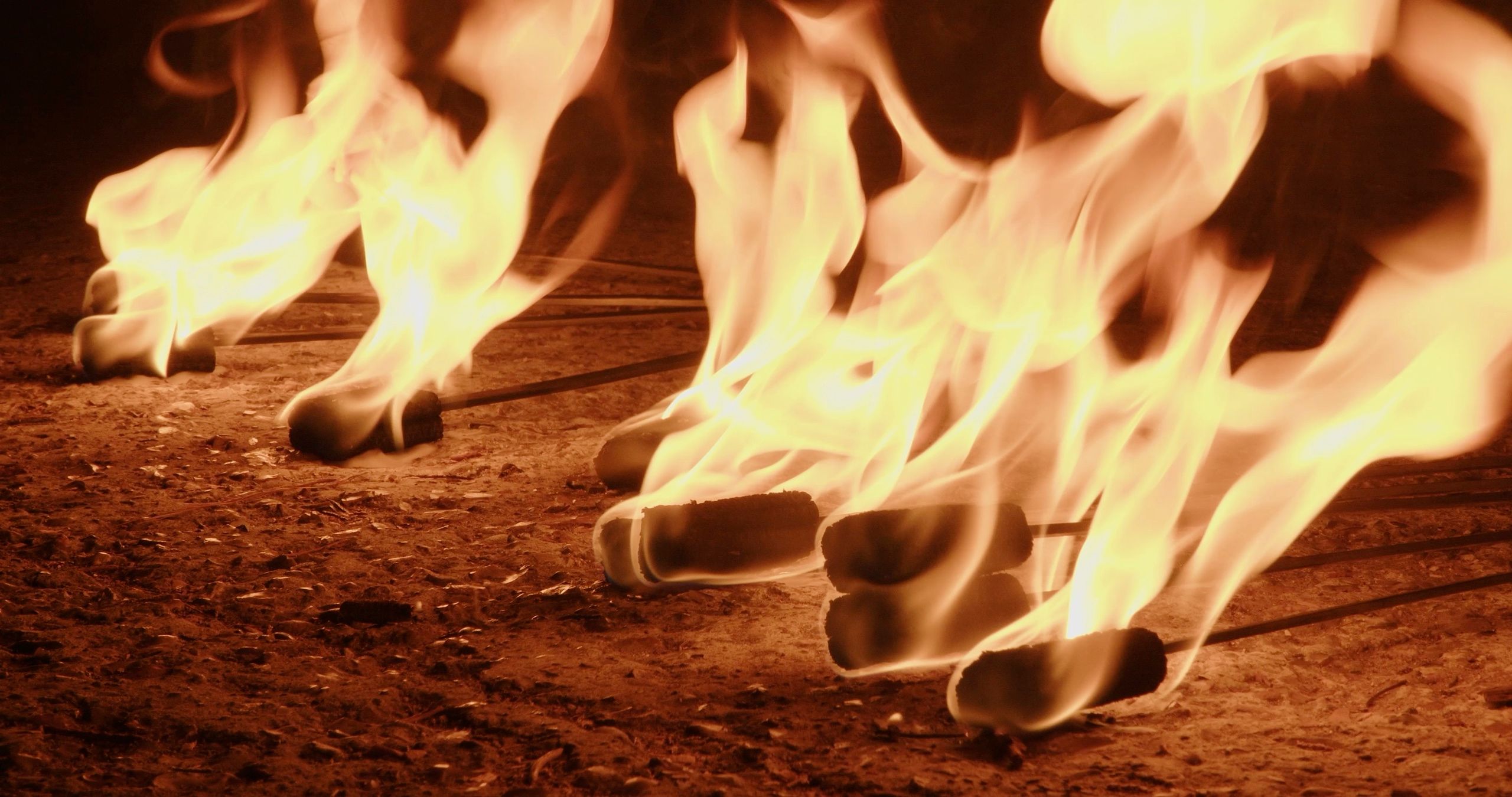 La nuit, au ras du sol, les mèches de plusieurs bâtons de feu brûlent en grandes flammes sur la terre battue.