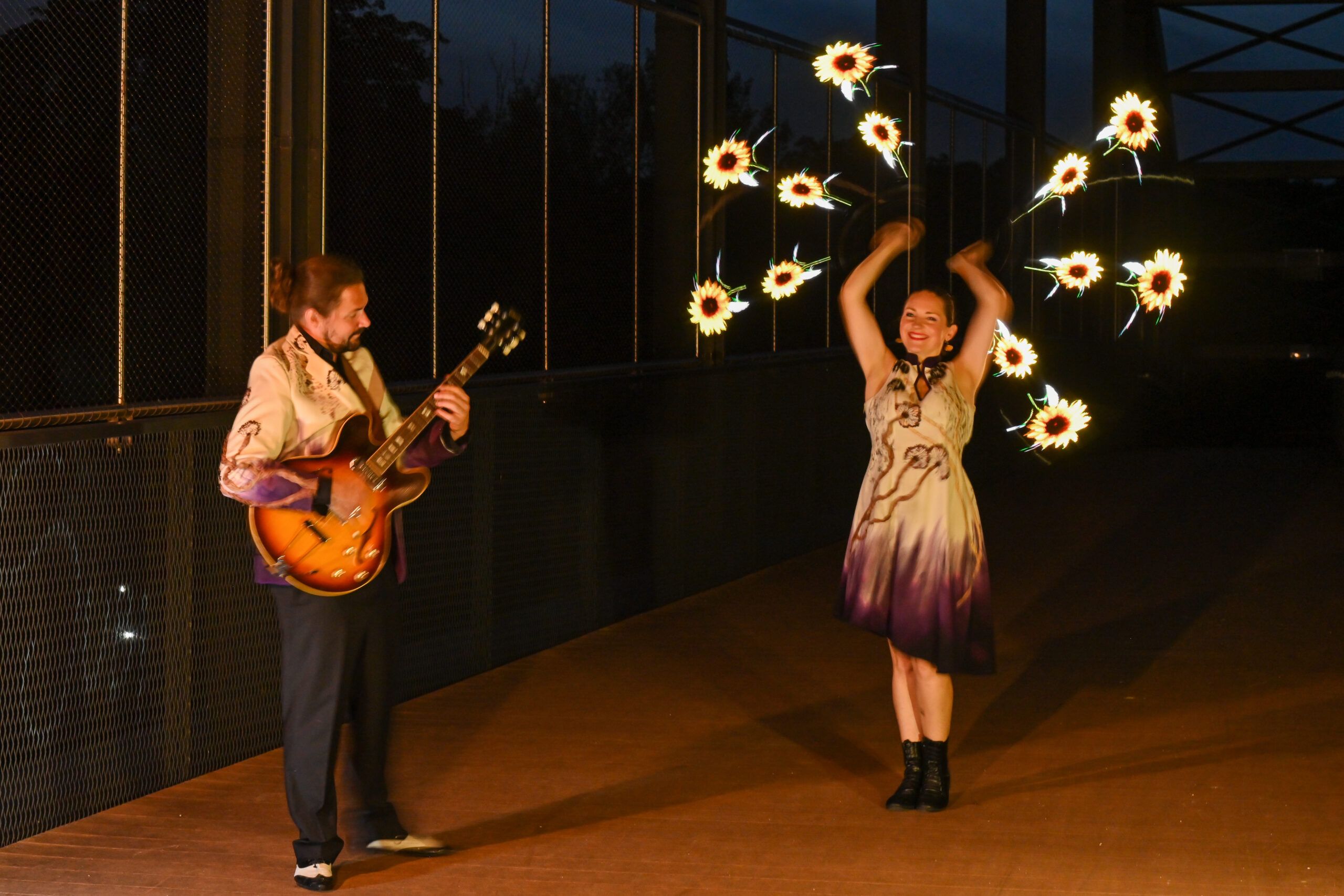 Le guitariste et la danseuse aux poïs lumineux, de nuit.