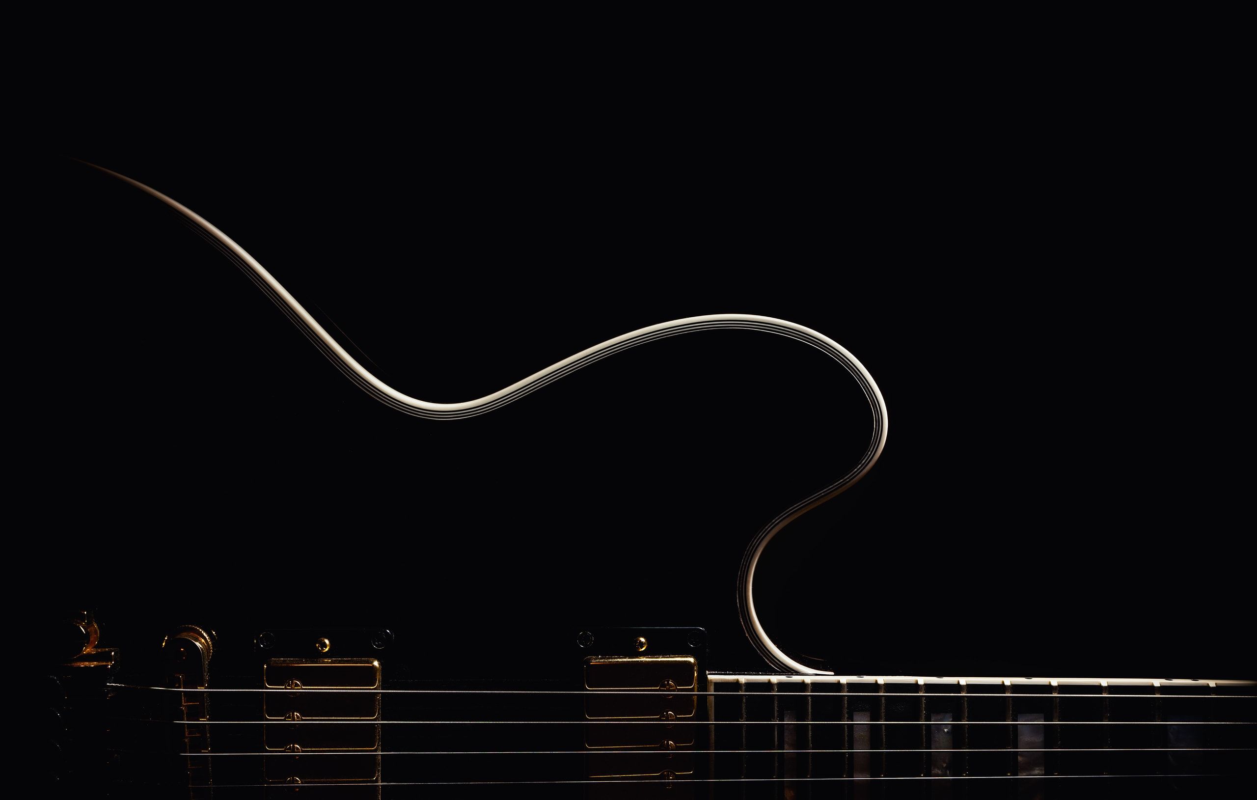 Dans l’ombre, le filet clair qui borde une guitare demi-caisse noire, au-dessus de ses cordes.