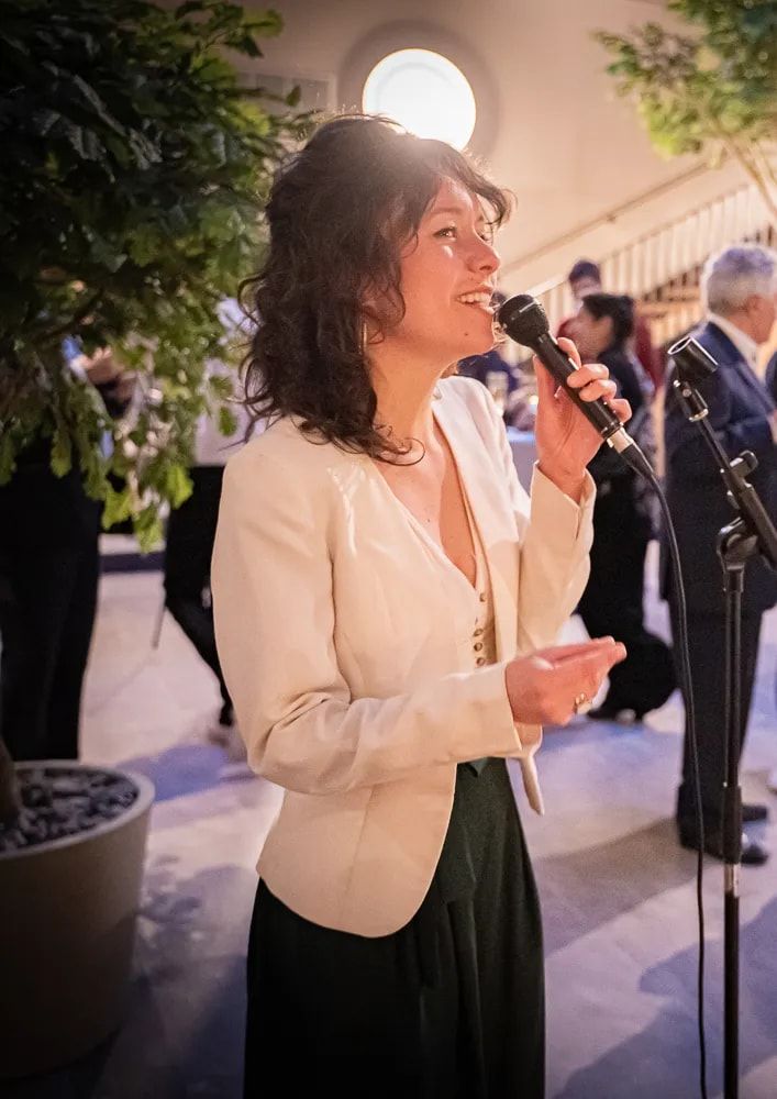 Louise Robard chante, micro en main, lors d’une réception.