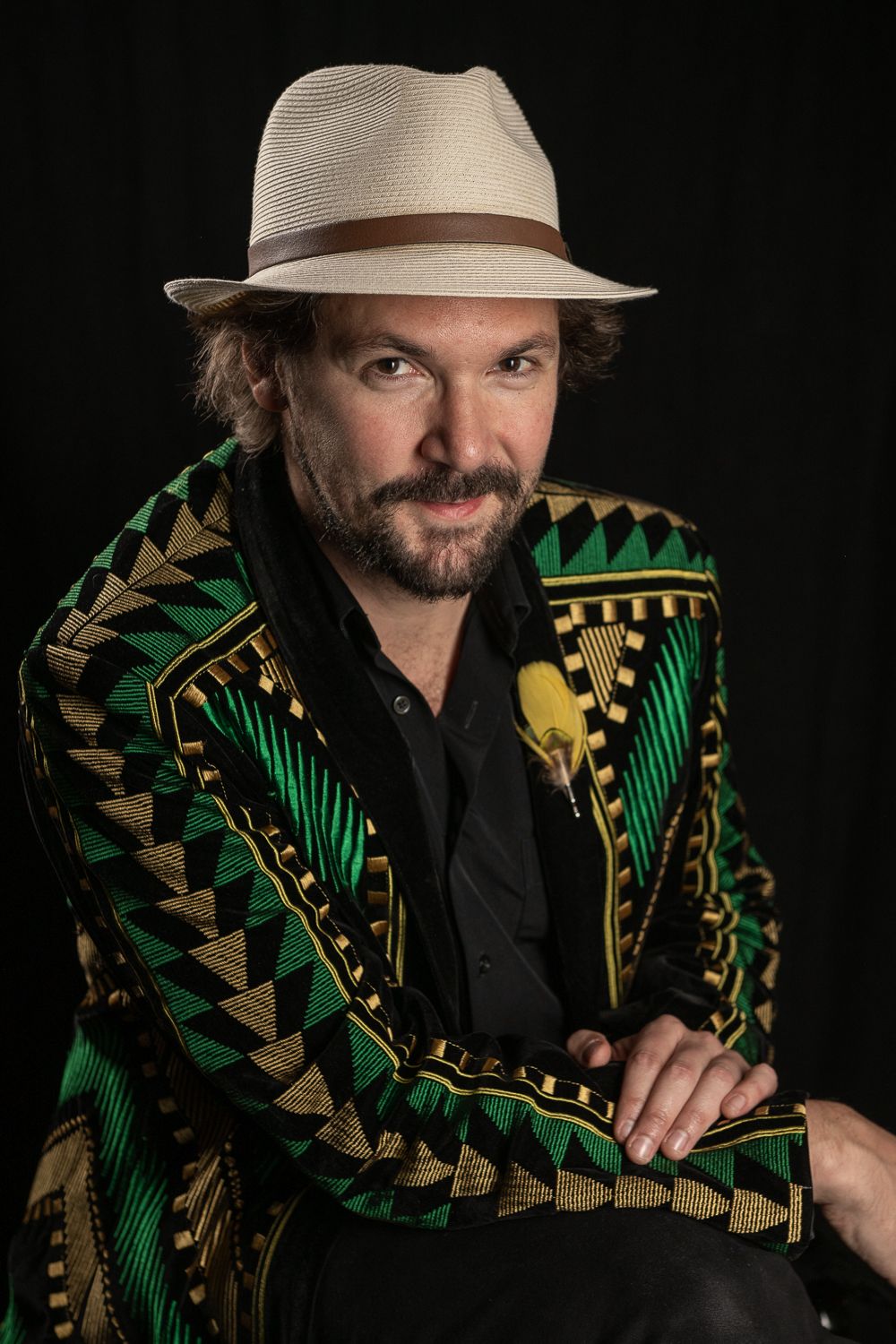 Mathieu Crochemore, chapeau clair et veste à motifs verts et dorés.