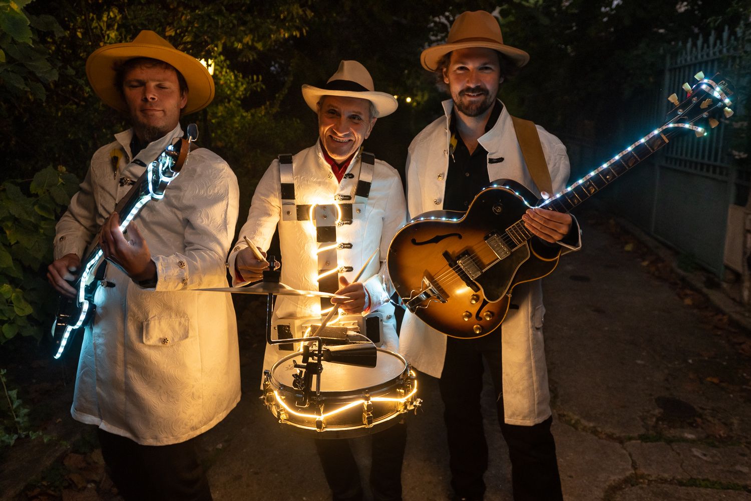La nuit, les musiciens de Streetside en costumes blancs parés de leds.