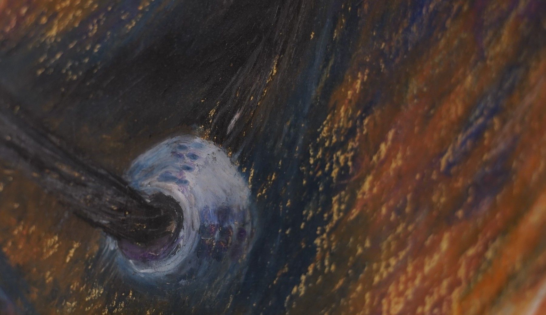 Détail du portrait au pastel accroché dans le salon : une perle bleu pâle au bout d’un cordon noir, sur des hachures orange.