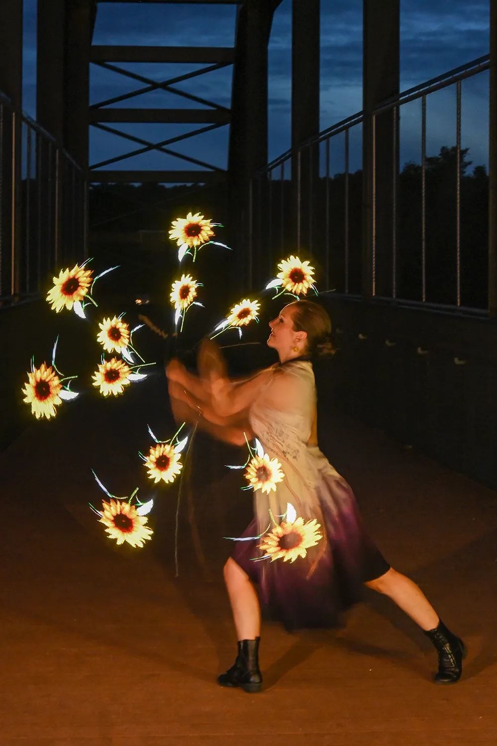 La danseuse fait tourner des poïs lumineux : des fleurs de lumière s’allument autour d’elle.