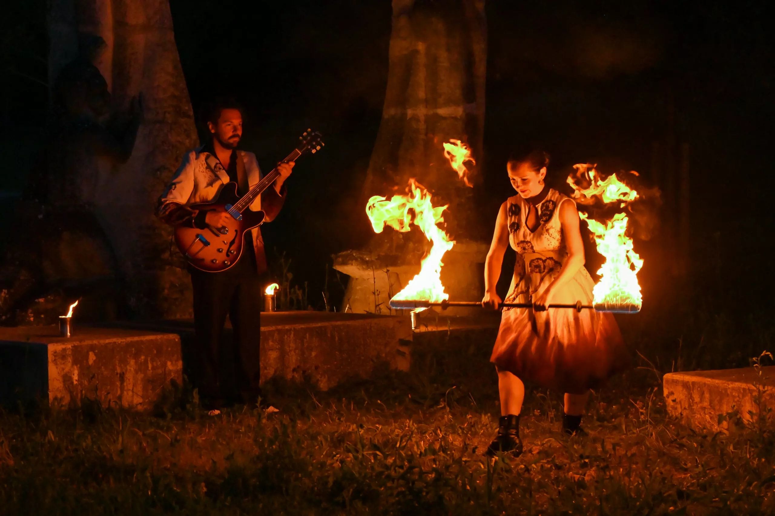 La nuit, le guitariste joue pendant que la danseuse tient devant elle deux éventails de feu.